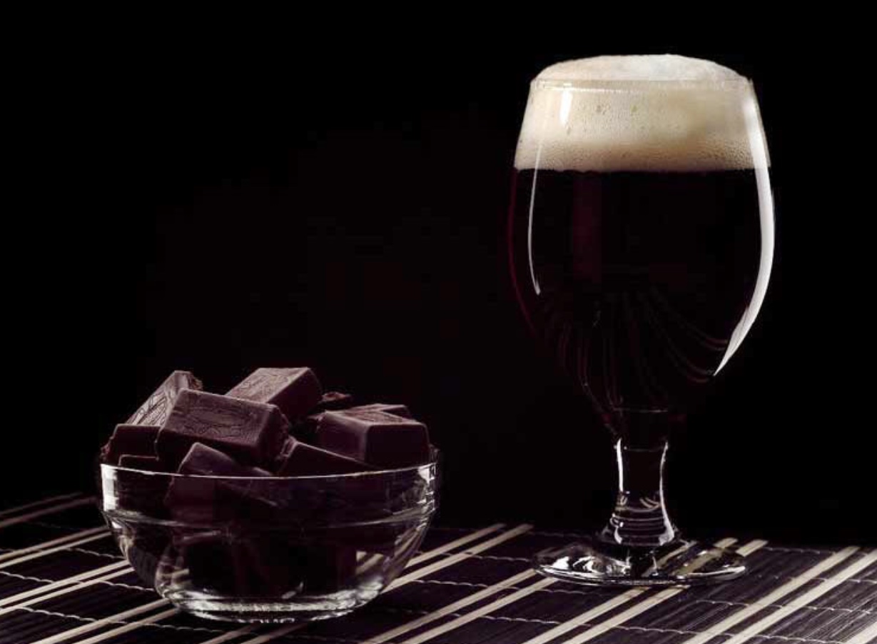 A glass of beer and bowl of chocolate.